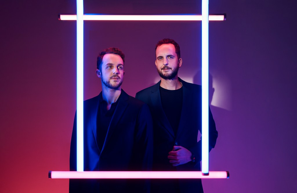 Robbie Ferguson (left), James Ferguson (right). They are posing behind a square frame made out of light beam.