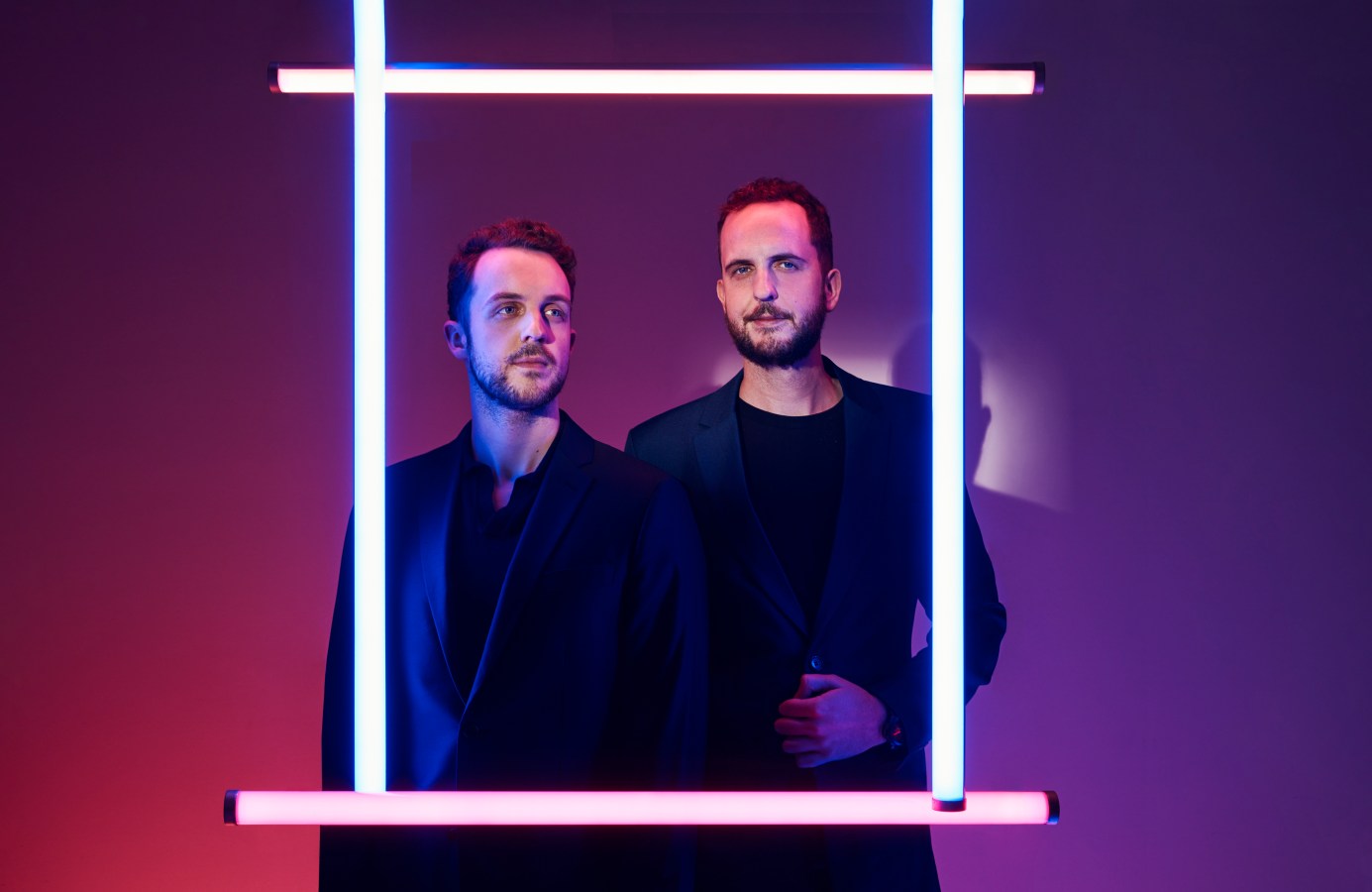 Robbie Ferguson (left), James Ferguson (right). They are posing behind a square frame made out of light beam.