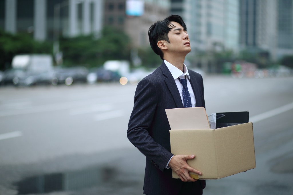 Asian man in suit on the street carrying box of work belongings