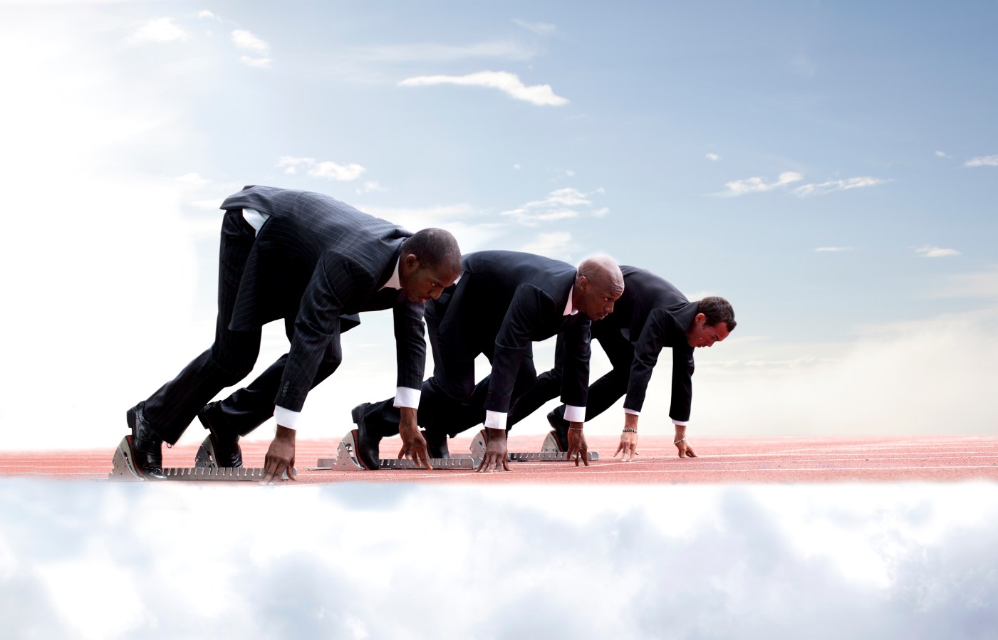 Businessmen on start line of running track,