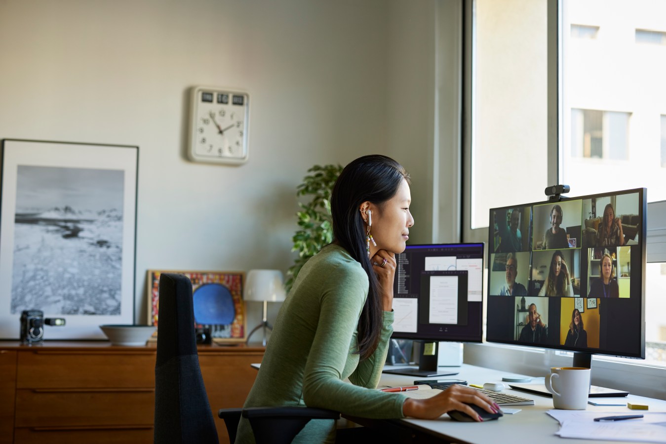 Woman working from home in front of computer showing team meeting participants.