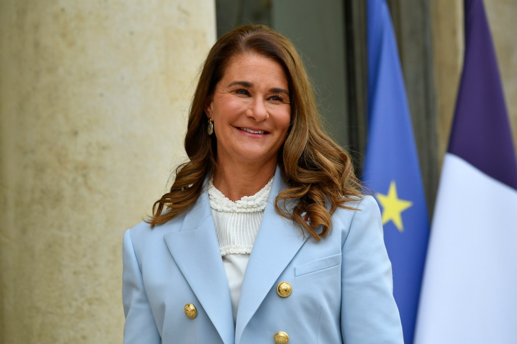 Melinda Gates arrives at Elysee Palace for the Generation Equality Forum hosted by French President Emmanuel Macron. She is wearing a blue blazer, and a white top underneath. Her top is white and she is smiling.