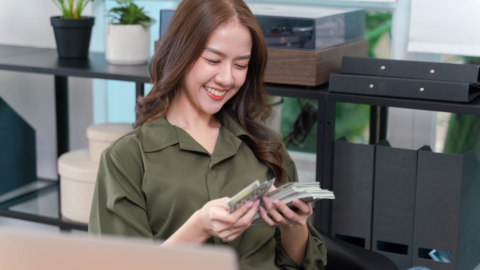 woman counting money in an office in front of files