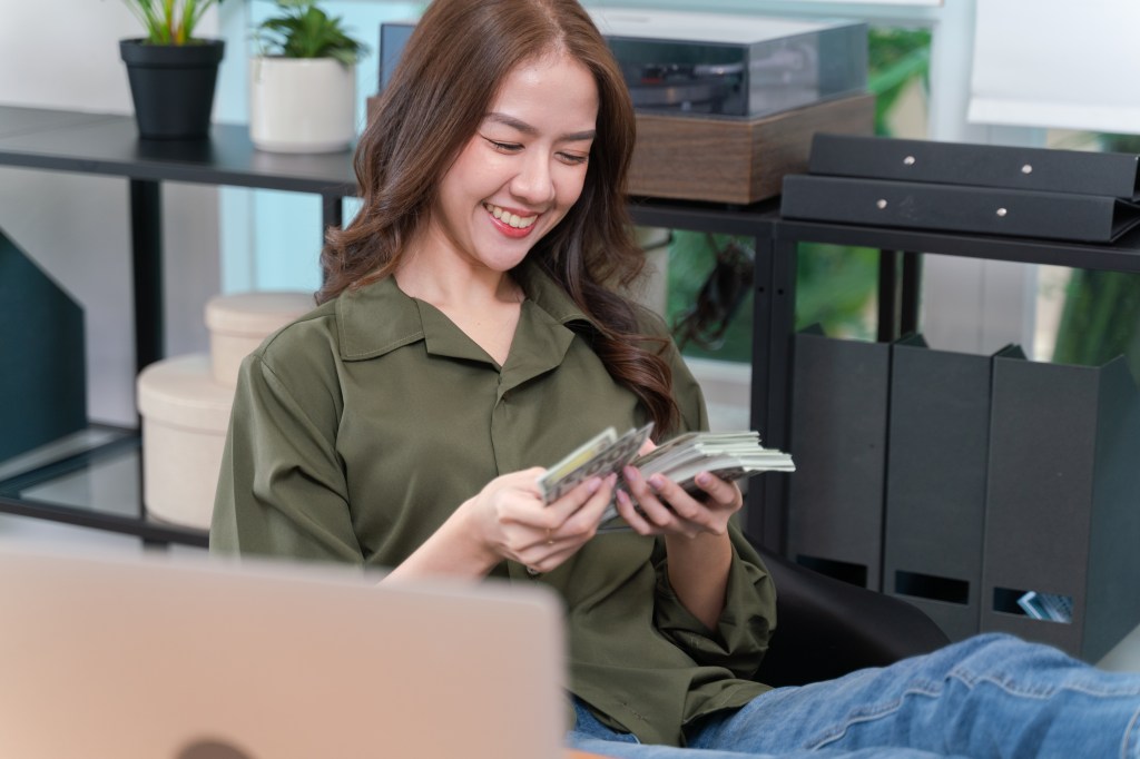 woman counting money in an office in front of files