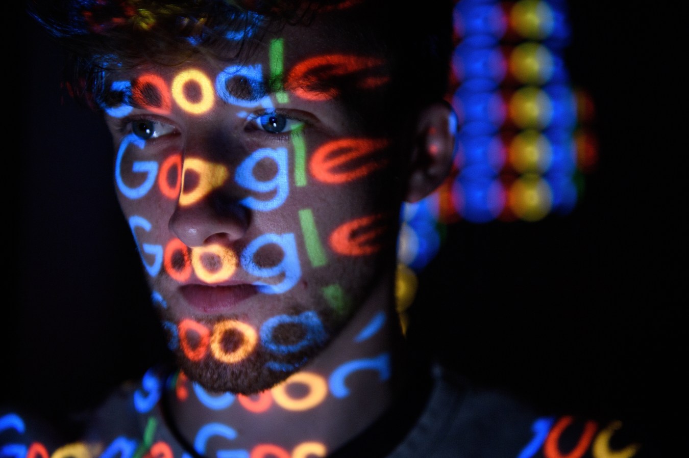 The Google logo is projected onto a person's face