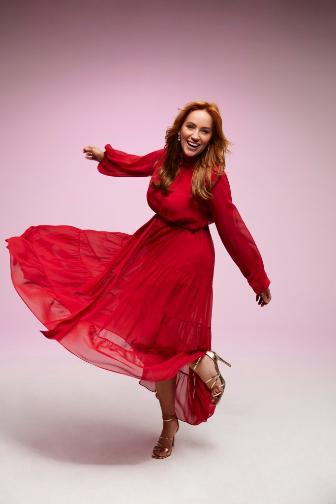 Jules Robinson is wearing a long, red dress. She is dancing, and has her arms out to the side.