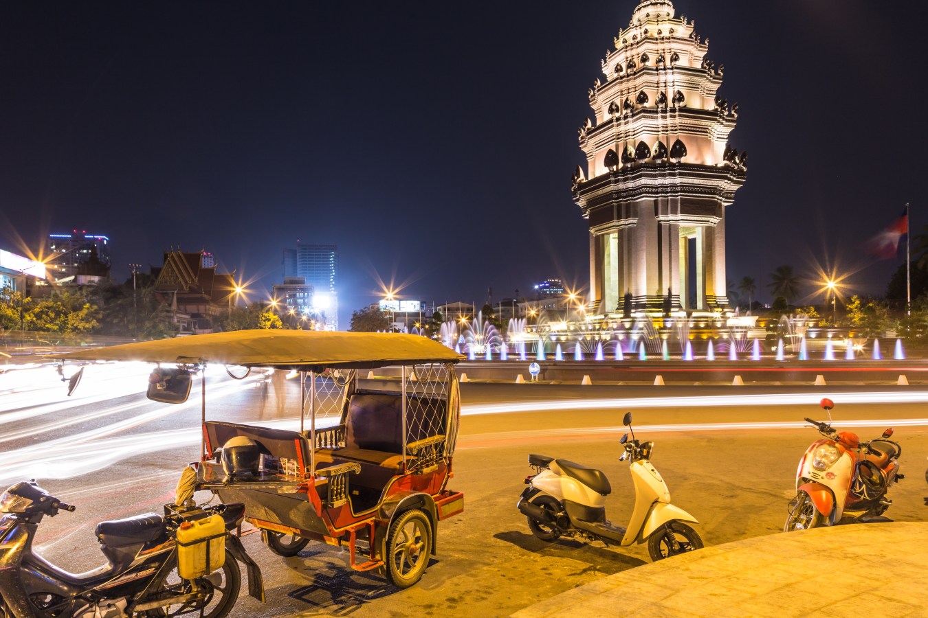 Tuk Tuk parked in front of the Independence monument, inspired by Khmer traditional architecture, in Phnom Penh, Cambodia capital city at night.