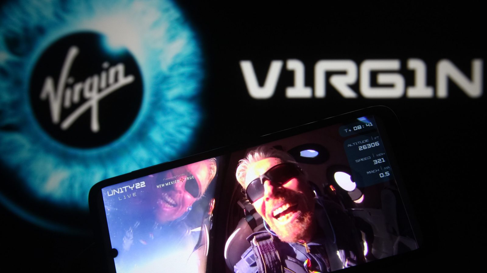In this photo illustration, British billionaire Richard Branson is seen on a fragment of a Virgin Galactic Unity 22 Spaceflight Livestream Youtube video displayed on a smartphone with the Virgin Galactic logo in the background.