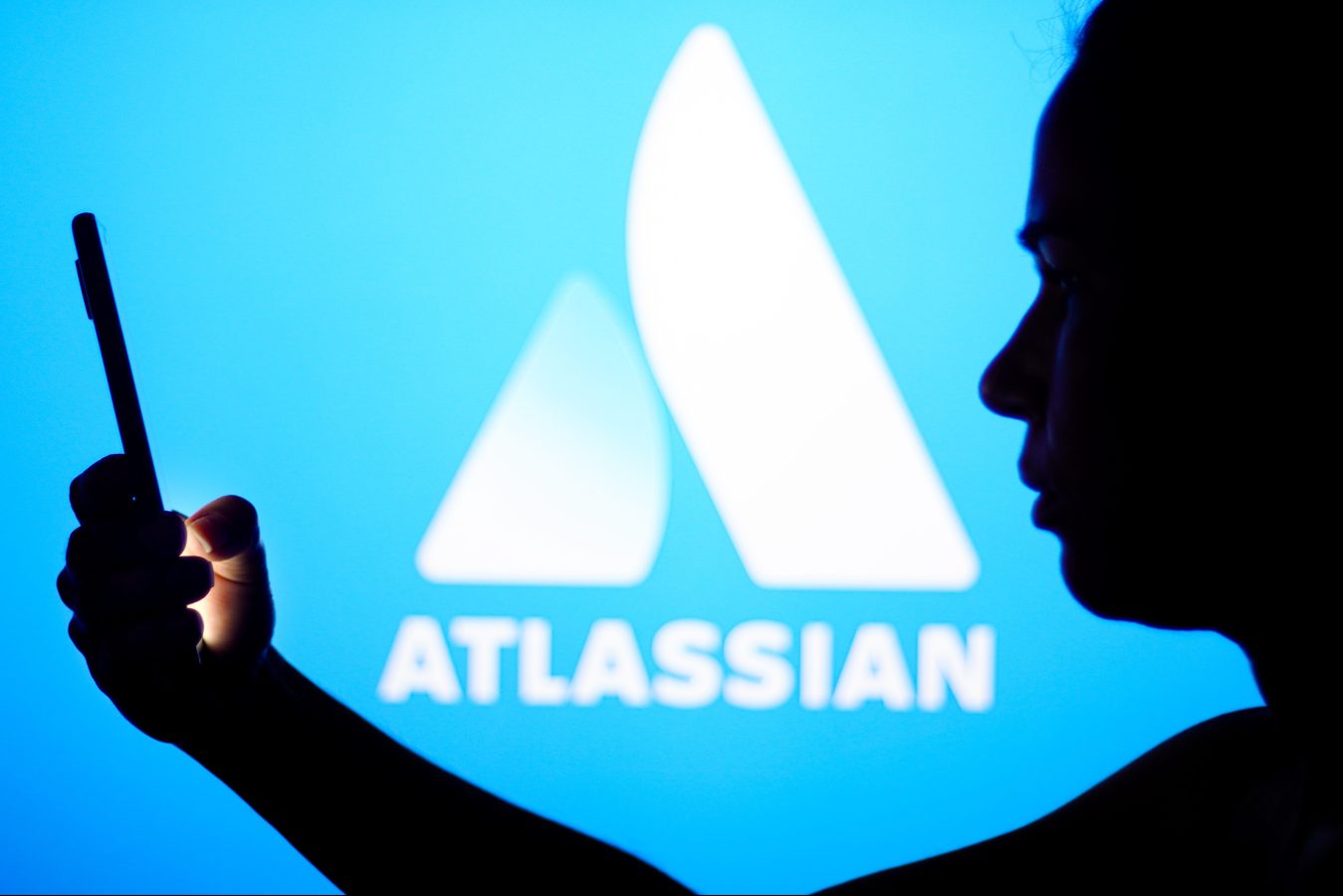 BRAZIL - 2022/05/30: In this photo illustration, the Atlassian Corporation logo is seen in the background of a silhouetted woman holding a mobile phone. (Photo Illustration by Rafael Henrique/SOPA Images/LightRocket via Getty Images)