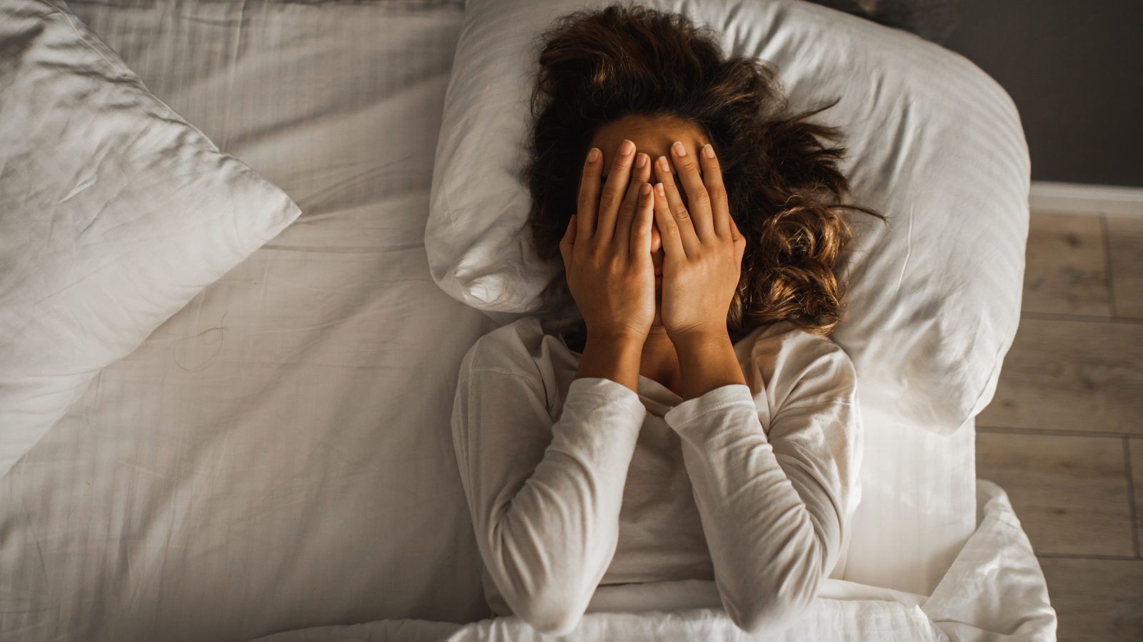 Woman lying in bed hands over face