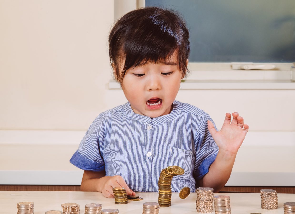 Child playing with coins/ Changing your relationship with money will take a conscious and consistent effort.