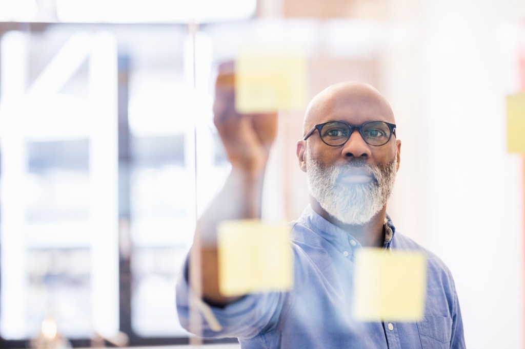 man swipes screen showing notes on the glass