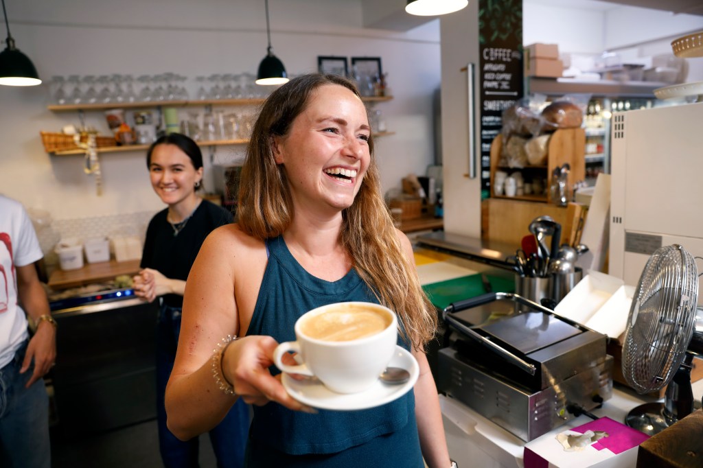 smiling waitress serves coffee in cafe