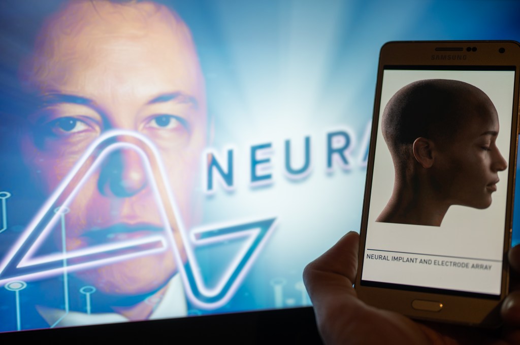 Neuralink logo displayed on mobil with founder Elon Musk seen on screen in the background. Neuralink Corporation is a neurotechnology company that develops implantable brain-computer interfaces. In Brussels on 4 December 2022.  (Photo Illustration by Jonathan Raa/NurPhoto via Getty Images)