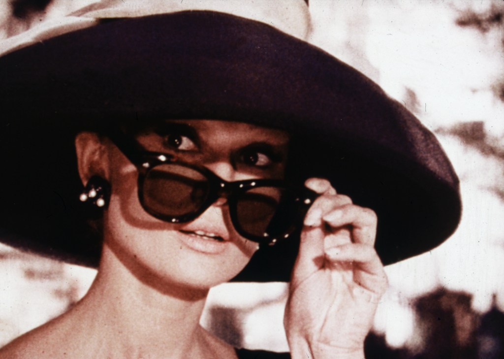 1961:  Belgian-born actor Audrey Hepburn (1929 - 1993) lowers her sunglasses in a still from director Blake Edwards' film, 'Breakfast at Tiffany's.'  (Photo by Paramount Pictures/Fotos International/Getty Images)