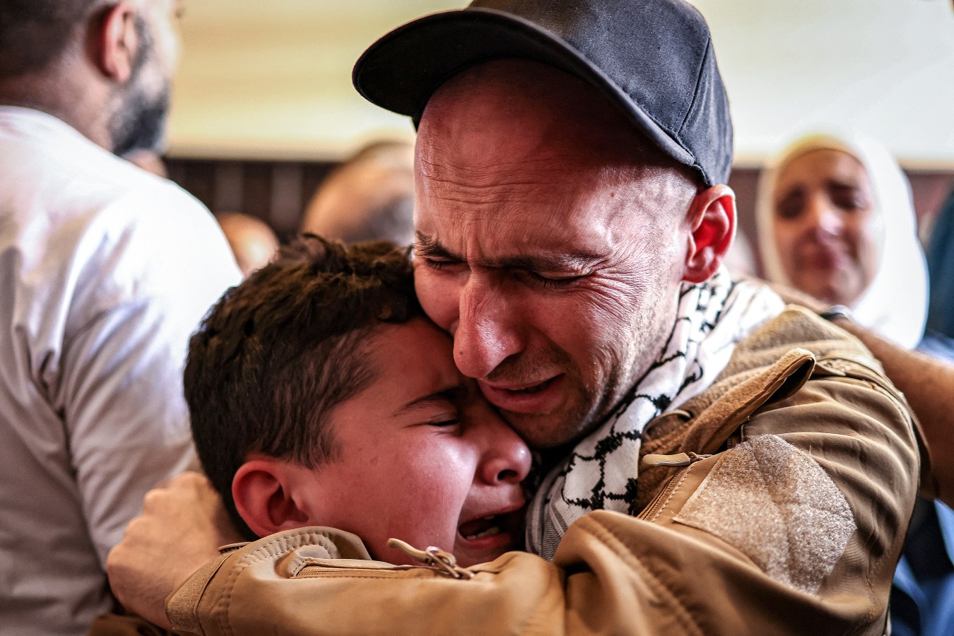 TOPSHOT - One of the Palestinian prisoners, who was released in a prisoner-hostage swap and ceasefire deal between Israel and Hamas, embraces a boy upon arrival by bus at Ramallah Cultural Centre in Ramallah in the occupied West Bank, on October 13, 2025, coming from Ofer military prison in the Israel-occupied Palestinian territories. The initial stage of the Gaza ceasefire deal includes the release of 47 Israeli living and dead hostages taken on October 7, 2023 in exchange for 250 prisoners and 1,700 Gazans held by Israel since the war broke out. (Photo by Zain JAAFAR / AFP) (Photo by ZAIN JAAFAR/AFP via Getty Images)