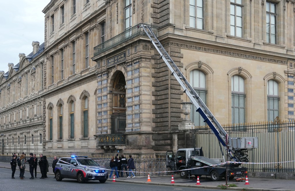 French police officers stand next to a furniture elevator used by robbers to enter the Louvre Museum.