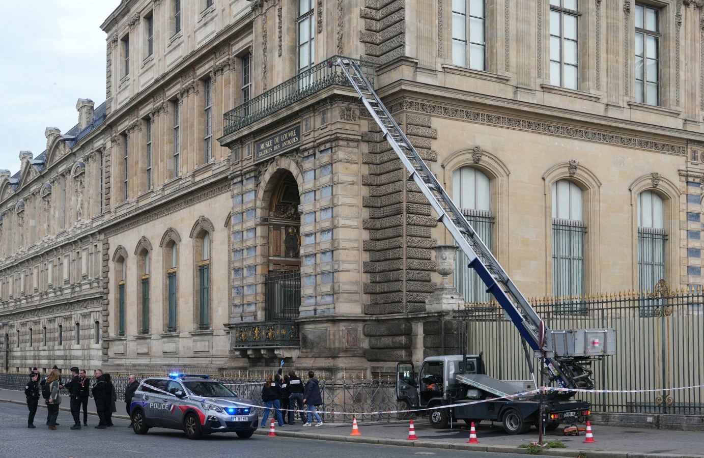 French police officers stand next to a furniture elevator used by robbers to enter the Louvre Museum.